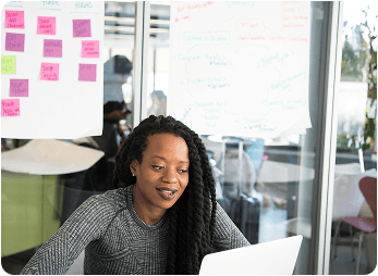 Professional woman smiling while working on laptop in modern office